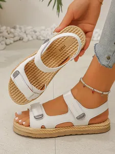 Dettaglio di sandali bianchi con zeppa, cinturini in velcro e suola a trama intrecciata