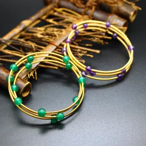 Détail de bracelets 3 couches plaqués or 24 carats avec pierres naturelles vertes et violettes.