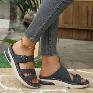 Close-up of navy blue wedge platform sandals with buckle detail on model's feet.