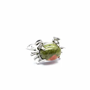Detailansicht eines silbernen Krabbenrings mit einem grünen Unakit-Stein.
