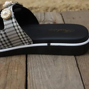 Dettaglio di sandalo da donna in stile francese con perle e cinturino a quadri.