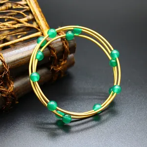 Détail d'un jonc à 3 couches plaqué or 24 carats avec perles en pierre naturelle verte.