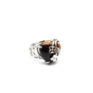 Close-up of heart-shaped brown tiger eye stone ring with silver flower accents
