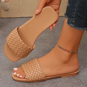 Detailed view of women's summer flat slides featuring a tan woven strap and slim sole.