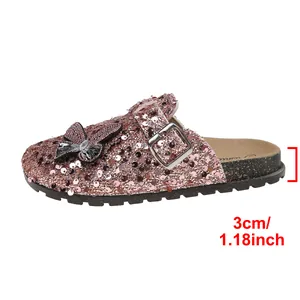 Detail view of pink sequined mule slippers with 3cm heel height and butterfly accent
