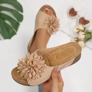 Close-up of beige wedge platform slippers with oversized textile flower decoration