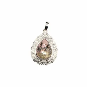Detail view of a vintage style teardrop natural stone pendant with silver filigree edge