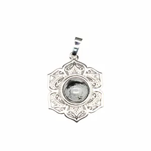 Gros plan d'un pendentif mandala argenté avec une perle de cristal au centre.