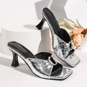 Macro view of silver crocodile texture high-heeled sandals with square toe and metal buckle.