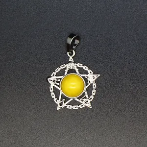 Detailopname van een zilveren pentagram hanger met een gele steen en occulte symbolen.