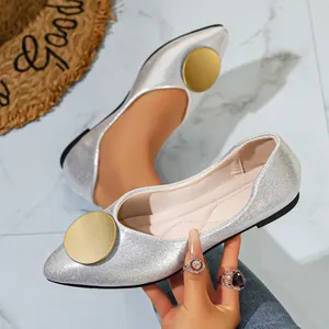 Primer plano de elegantes zapatos planos plateados en punta con hebilla dorada.