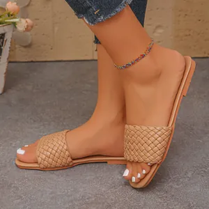 Close-up of stylish women's beige braided flat sandals featuring a textured woven strap