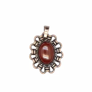 Detailansicht eines Vintage-Anhängers mit ovalem rotem Naturstein und Ornamenten