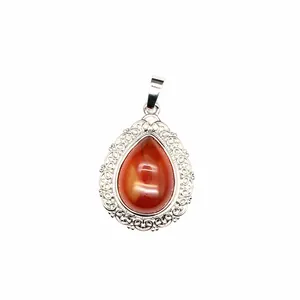Close-up of teardrop-shaped natural stone pendant with intricate filigree silver border.
