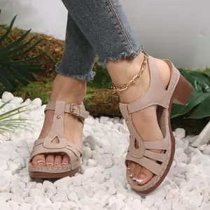 Detail view of beige T-strap chunky heel sandals worn on model with gold anklet