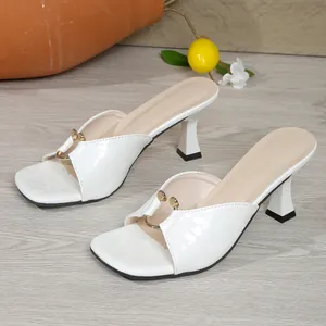 Detail of white crocodile patterned square toe mules with gold metal ring decoration.