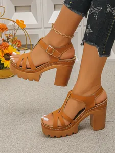 Detail van bruine platformsandalen met dikke hakken en witte stiksels op een model.