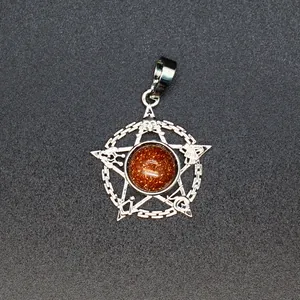 Detailopname van een zilverkleurige pentagram hanger met een sprankelend goudsteen midden.