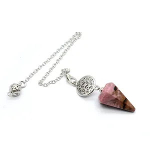 Gros plan d'un pendule hexagonal en pierre naturelle rose avec breloque Fleur de Vie.