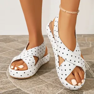 Gros plan de sandales à plateforme à pois blancs avec brides croisées et bout ouvert