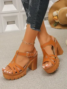 Detailopname van bruine dames sandalen met plateauzool en dikke hak met uitsnijdingen