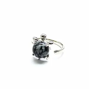 Detailaufnahme eines silbernen Schildkrötenrings mit rundem Schneeflocken-Obsidian-Stein.