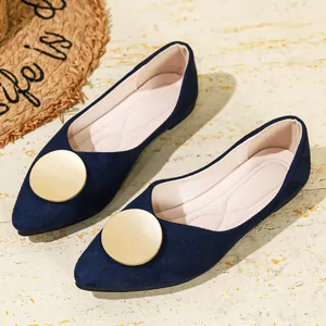 Primer plano de bailarinas de gamuza azul marino con elegante hebilla circular dorada.