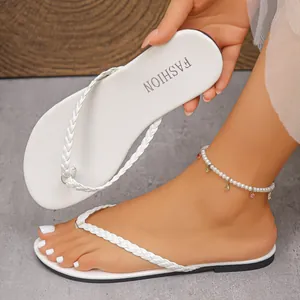 Close-up of white flat flip-flops with braided straps showing the sole and foot display.