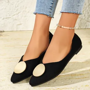 Primer plano de zapatos planos negros de punta con hebillas circulares doradas grandes.