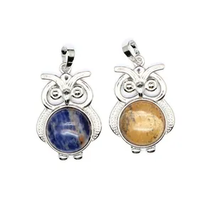 Dettaglio macro di pendenti a forma di gufo in argento con pietre naturali blu e gialle
