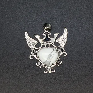 Primer plano detallado de un colgante de plata con corona y alas y piedra de corazón blanca