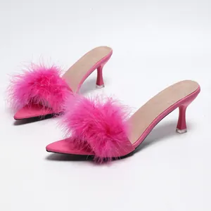 Dettaglio ravvicinato di sabot rosa con tacco alto e punta a punta con piume eleganti.