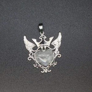 Detalle del colgante de piedra natural en forma de corazón con corona y alas plateadas