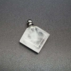 Primer plano de un colgante de frasco de perfume de cristal blanco en forma de rombo.