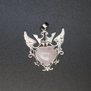 Primer plano de un colgante de cuarzo rosa en forma de corazón con alas y corona plata