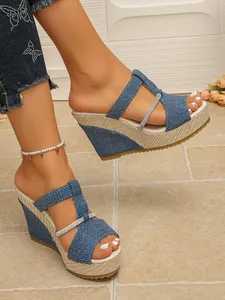 Nahaufnahme von stilvollen blauen Denim-Keilsandalen mit funkelnden Strassriemen