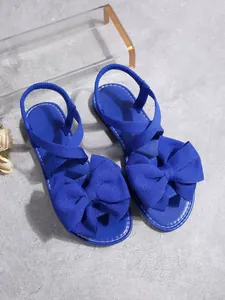 Detailansicht der hellblauen flachen Sandalen mit einer großen dekorativen Stoffschleife