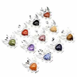 Detalle de varios colgantes de corazón de piedra natural con diseños de alas de plata