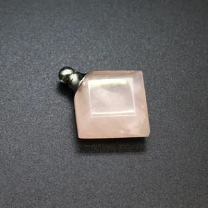 Detalle macro de un colgante frasco de perfume de cuarzo rosa rómbico con tapón plateado