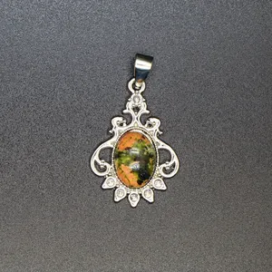 Detailed close-up view of a vintage unakite stone pendant with silver filigree frame