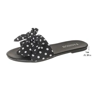 Side view of black polka dot bow flat slide sandal with 1cm heel height annotation.