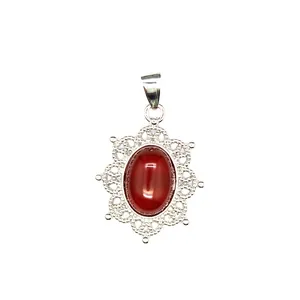 Macro detail of an intricate silver filigree pendant featuring a red oval natural stone
