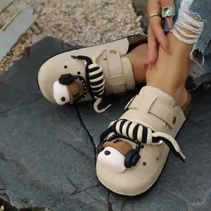 Detailed view of beige platform clogs featuring a 3D bear charm and thick rope laces