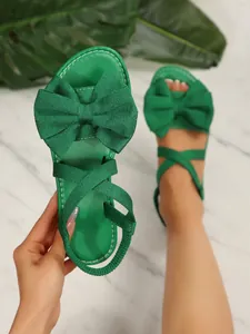Detailansicht der leuchtend grünen flachen Sandalen mit großer Schleife und Gummiband