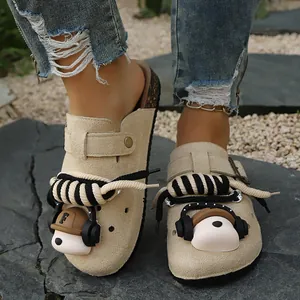 Detailed view of beige suede mules with unique bear and rope decorations