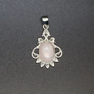 Macro view of vintage silver pendant featuring oval pink gemstone and crystal accents