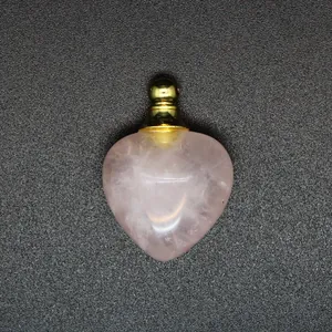Dettaglio ravvicinato di un ciondolo diffusore di oli essenziali in quarzo rosa a cuore.