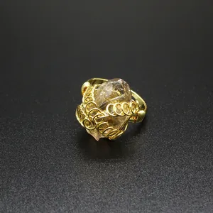 Dettaglio ravvicinato di un anello regolabile fatto a mano con cristallo grezzo avvolto in oro.