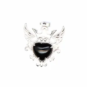 Detalle macro de un colgante gótico de plata con corona, alas y una piedra de corazón negro