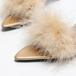 Dettaglio di eleganti sabot dorati a punta con rifiniture in soffici piume color champagne